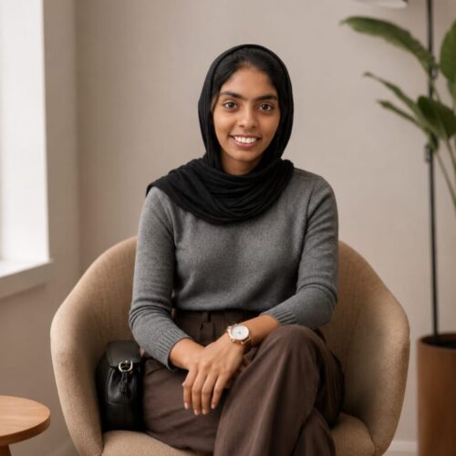 Best Digital Marketing Strategist in Kannur, Ziya Fathima, smiling while seated in a modern office wearing a black hijab and professional attire.