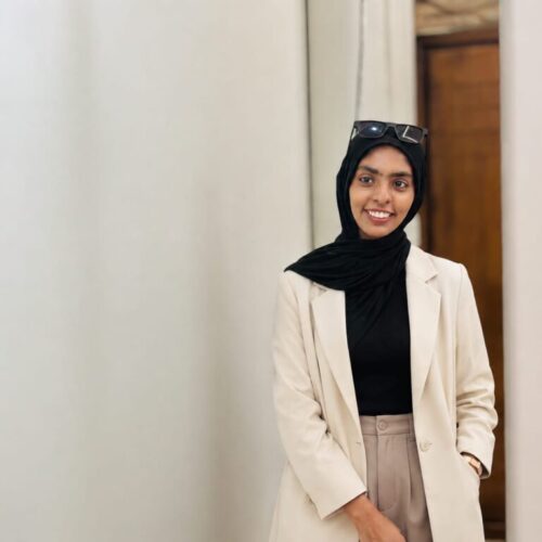 Best Digital Marketing Strategist in Kannur, Ziya Fathima, smiling while seated in a modern office wearing a black hijab and professional attire.
